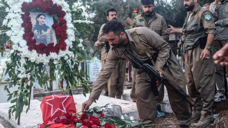 مقاتلون أكراد يضعون وروداً على قبر مغطى بعلم حزب العمال الكردستاني PKK في مراسم تأبين تعكس التوترات الإقليمية بين تركيا وإيران.