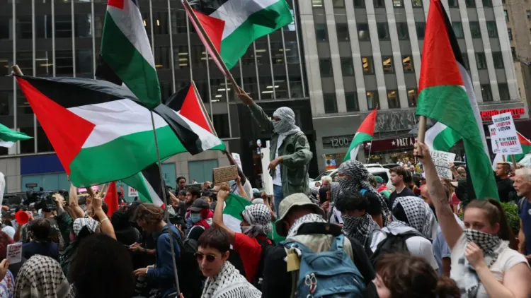 تجمع حشود من المتظاهرين يحملون الأعلام الفلسطينية في احتجاج يعبر عن التضامن مع فلسطين، وسط أجواء حماسية في المدينة.