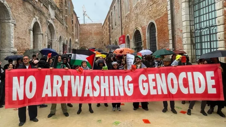 محتجون يحملون لافتة كبيرة كتب عليها "لا لتلميع الإبادة بالفن" أمام الجناح الإسرائيلي في "بيينالي البندقية"، خلال إضراب ثقافي.