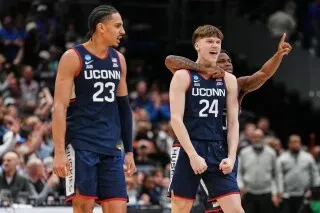 فريق UConn يحتفل بعد فوز مثير على Duke في بطولة NCAA، مع التركيز على اللاعبين في ملابس الفريق الرسمية.