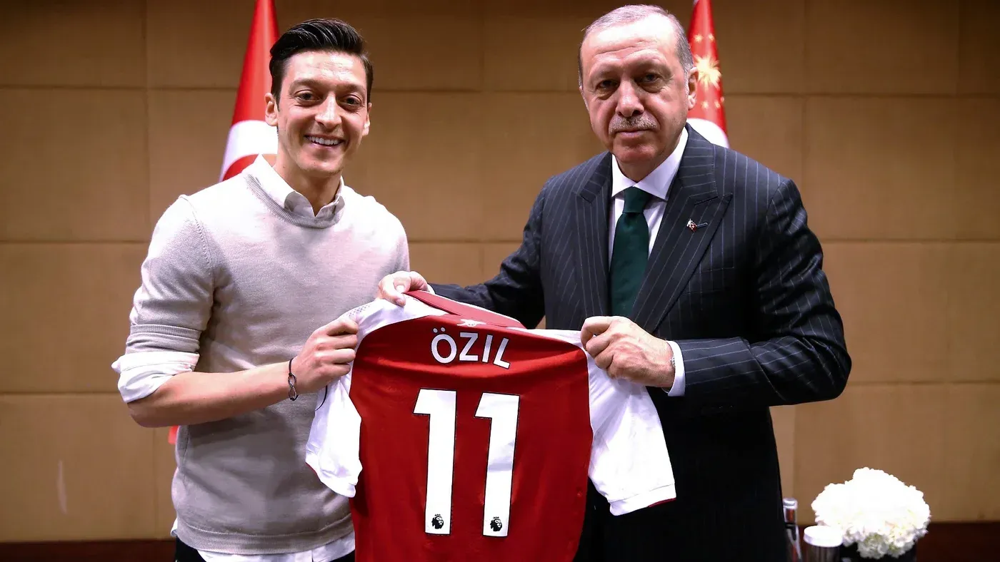 مسعود أوزيل، لاعب كرة القدم السابق، يقف مع الرئيس رجب طيب أردوغان، ممسكًا بقميص يحمل اسمه، في مؤتمر حزب العدالة والتنمية.