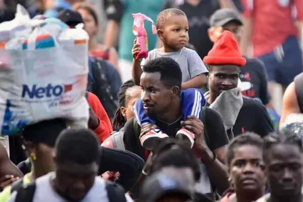 مجموعة من المهاجرين تسير في تاباتشولا بالمكسيك، مع طفل على كتف أحدهم، احتجاجًا على الانتظار الطويل للحصول على الوثائق اللازمة.