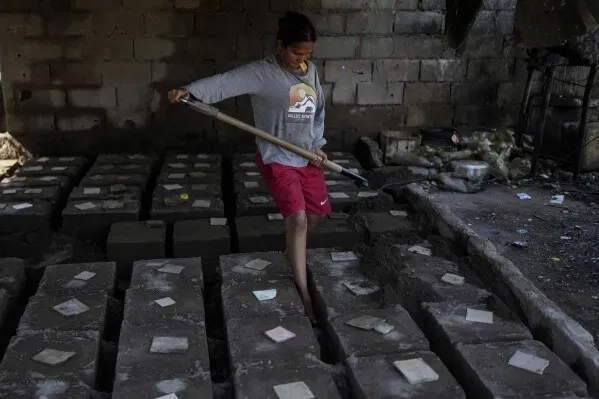 شاب يعمل في مصنع لإنتاج أواني الطهي من الألومنيوم في فنزويلا، محاط بأشكال الأواني الجاهزة.