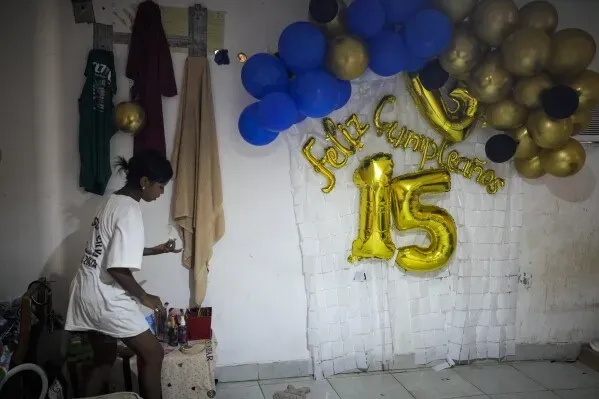 امرأة ترتب زينة لحفل عيد ميلاد، مع بالونات زرقاء وذهبية، وعبارة "فيلس كوميبلانوس 15" مكتوبة بخط كبير.