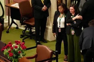 امرأتان تقفان بجوار طاولة مزينة بالورود في مبنى الكابيتول، في سياق مناقشات حول قضايا الهجرة والأمن في مينيسوتا.