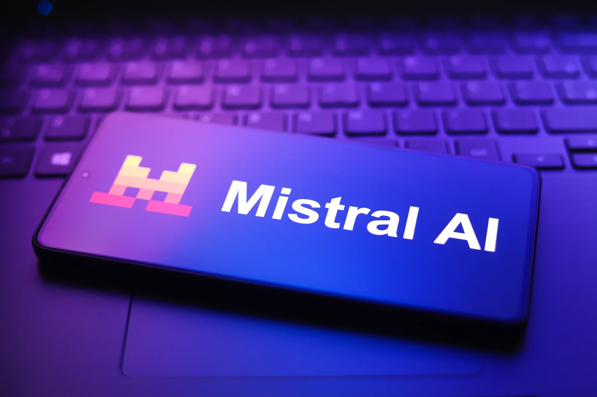 شعار Mistral AI على شاشة هاتف ذكي موضوع فوق لوحة مفاتيح، يرمز إلى نموذج الذكاء الاصطناعي متعدد الوسائط الجديد Mistral Large 4.