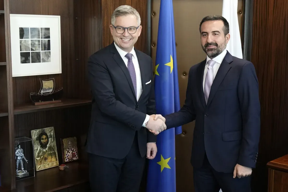 اجتماع بين نائب وزير الهجرة القبرصي نيكولاس يوانيدس والمفوض الأوروبي ماغنوس برونر، مع العلميات الأوروبية خلفهم.