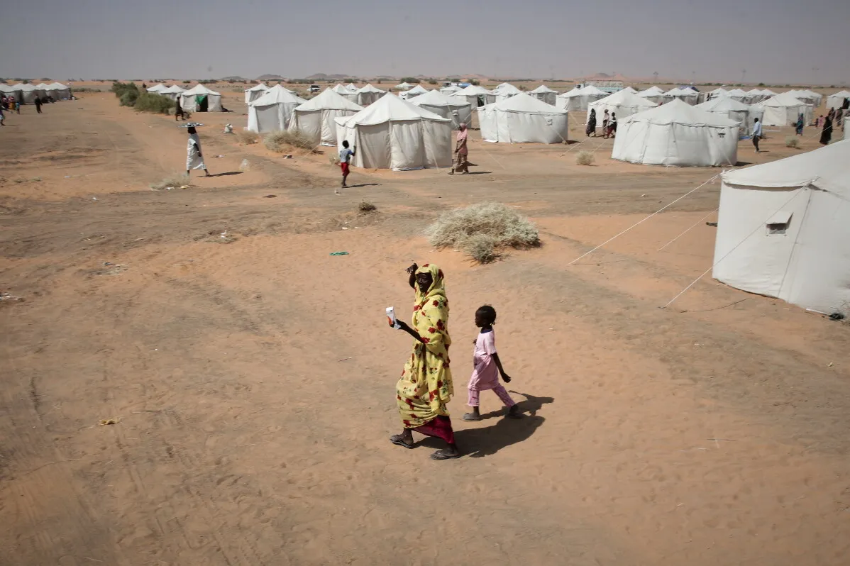امرأة وطفل يسيران في مخيم نزوح في السودان يعكس أزمة النزوح والحاجة الماسة للمساعدات الإنسانية للأطفال المتضررين من الحرب.