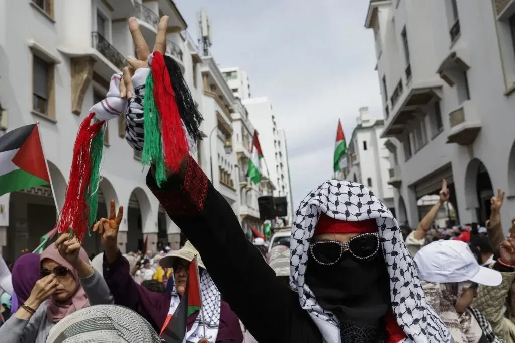 محتجون مغاربة يرفعون الأعلام الفلسطينية ويؤكدون دعمهم لفلسطين خلال تظاهرة ضد التطبيع مع إسرائيل في الشارع.