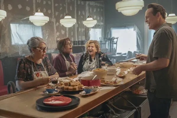 مشهد من فيلم "Nonnas" يظهر مجموعة من النساء الإيطاليات يتبادلن الضحك أثناء إعداد الطعام في مطبخ مطعم، مع وجود فينس فون.