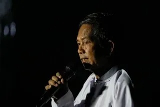 رجل يتحدث في تجمع انتخابي في يانغون، ميانمار، وسط أجواء مظلمة تعكس التوترات السياسية في البلاد بعد الانتخابات المثيرة للجدل.