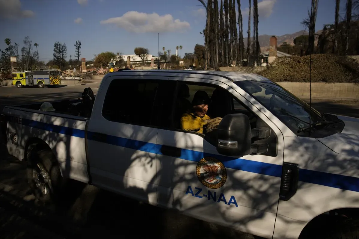 سيارة نقل تابعة لكشافة نافاجو تحمل شخصًا يرتدي زي الإطفاء، وتظهر خلفها آثار الدمار الذي خلفه حريق إيتون في لوس أنجلوس.