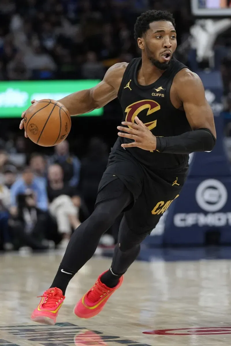 دونوفان ميتشل لاعب كليفلاند كافالييرز يت dribble الكرة في مباراة ضد مينيسوتا تمبروولفز، مع التركيز على الأداء القوي للفريق.