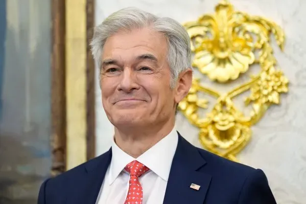 صورة لجيم بيلين، حاكم ولاية نبراسكا، مبتسمًا في حدث رسمي، حيث أعلن عن تطبيق متطلبات جديدة لبرنامج Medicaid.