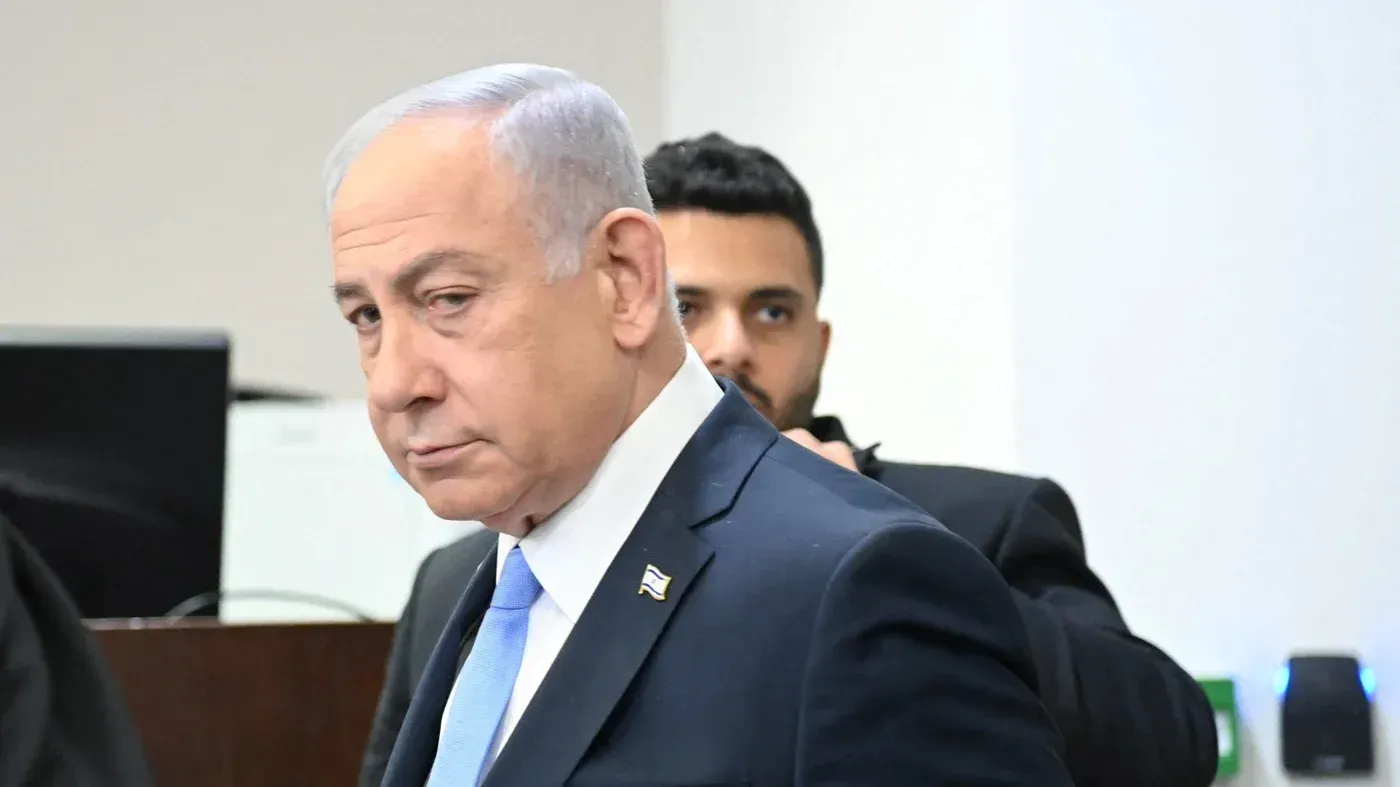 نتنياهو يظهر بوجه عابس خلال مؤتمر صحفي، مع وجود حراس خلفه، مما يعكس التوتر السياسي في ظل الأوضاع المتوترة في غزة.