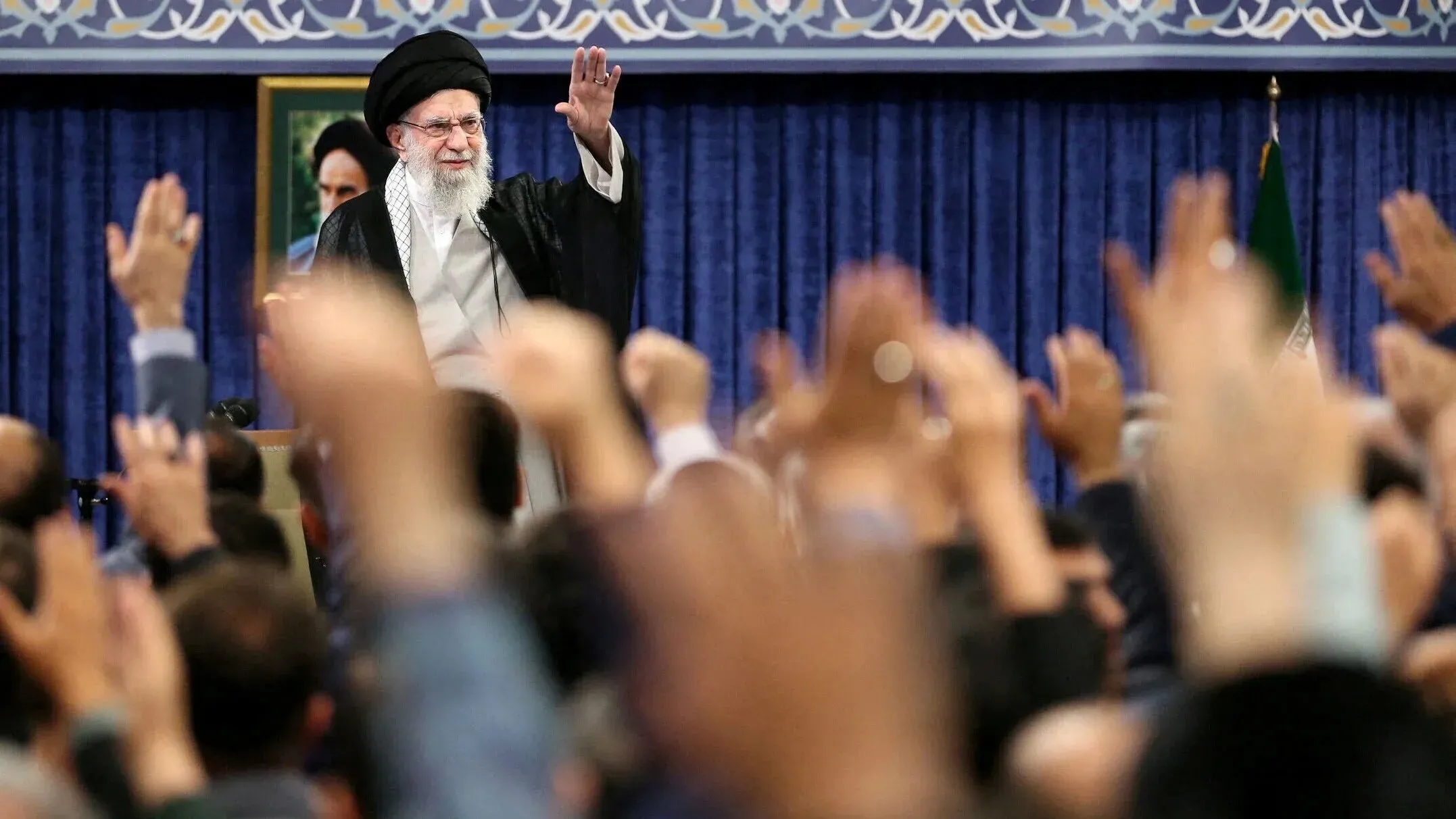 المرشد الأعلى الإيراني، آية الله علي خامنئي، يلوح بيده أمام حشد من المؤيدين في تجمع سياسي، مع التركيز على التوترات الإسرائيلية الأمريكية.