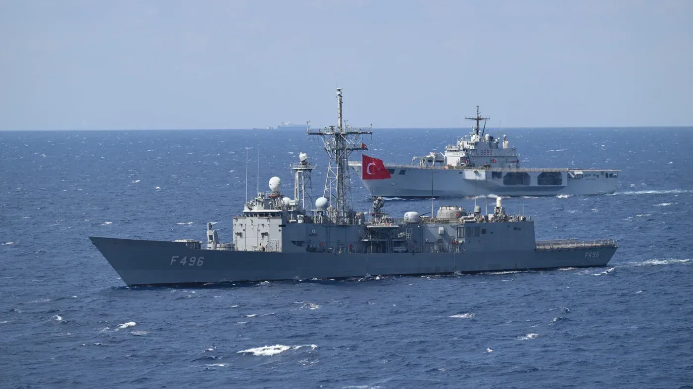 سفينتان حربيتان تركيتان في عرض البحر، تُظهران التقدم العسكري لتركيا، مع التركيز على حاملة الطائرات "Mugem" الجديدة.