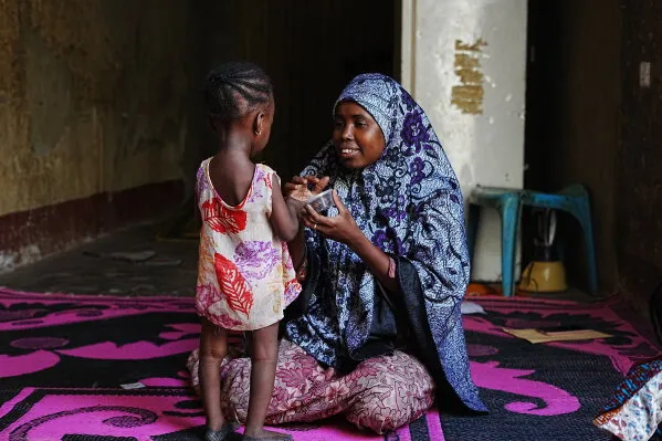 امرأة نيجيرية في منزل بسيط تتحدث مع طفلة صغيرة، تعكس معاناة الأسر من سوء التغذية والفقر في شمال نيجيريا.