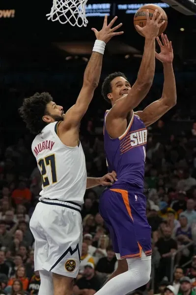 مباراة مثيرة بين دنفر ناجتس وفينيكس صنز، حيث يحاول لاعب صنز تسجيل سلة بينما يتصدى له جمال موراي من ناجتس.