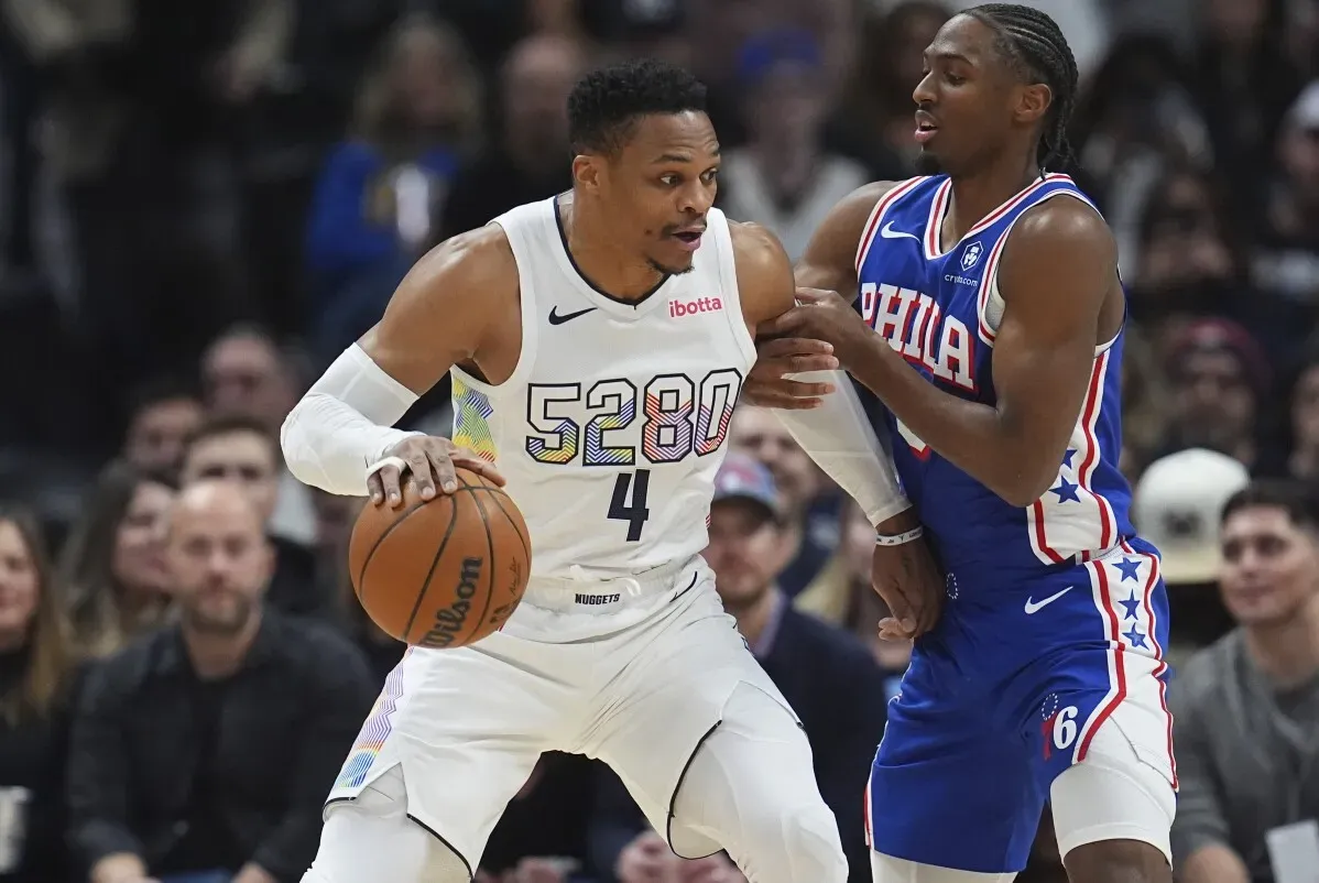 لاعب دنفر ناجتس يحمل الكرة ويتجاوز لاعب فيلادلفيا 76ers خلال مباراة، مع توضيح الحماس والتنافس.