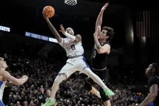 لاعب من فريق فلوريدا يسجل نقطة خلال مباراة ضد تكساس إيه آند إم، مع وجود لاعب منافس يحاول اعتراضه في أجواء حماسية.