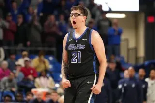 لاعب كرة سلة من فريق سانت لويس يحتفل بفوز فريقه، مرتديًا زيًا أسود يحمل الرقم 21، في أجواء حماسية بالملعب.