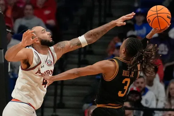 لاعب كرة سلة من فريق أوبورن يحاول صد تسديدة لاعب من ولاية ألاباما خلال مباراة في بطولة NCAA، مع وجود كرة سلة في الهواء.