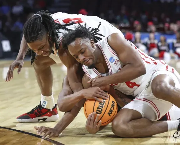 لاعبان من فريق هيوستن يتصارعان على الكرة خلال مباراة NCAA، مع التركيز على الجهد البدني والتنافسية في الجولة الأولى من البطولة.