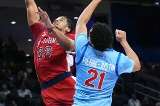 لاعب سانت جونز يسجل نقطة خلال مباراة ضد ديبول، حيث يظهر اللاعبان في لحظة تنافسية حماسية.