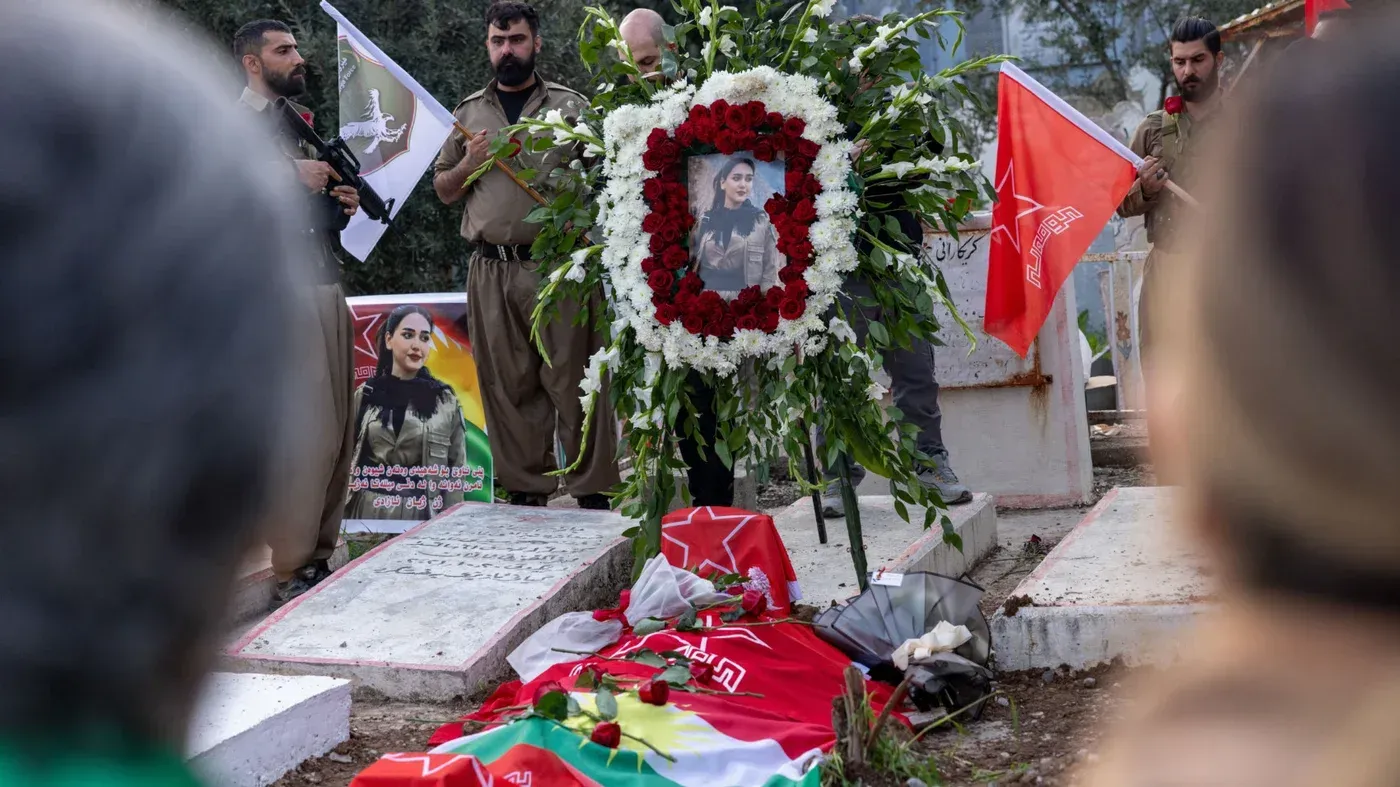 تجمع حشود في جنازة غزل مولان، مقاتلة كردية، مع زهور وشعارات حزبية، تأبينًا لها بعد مقتلها في ضربة بطائرة مسيّرة إيرانية.