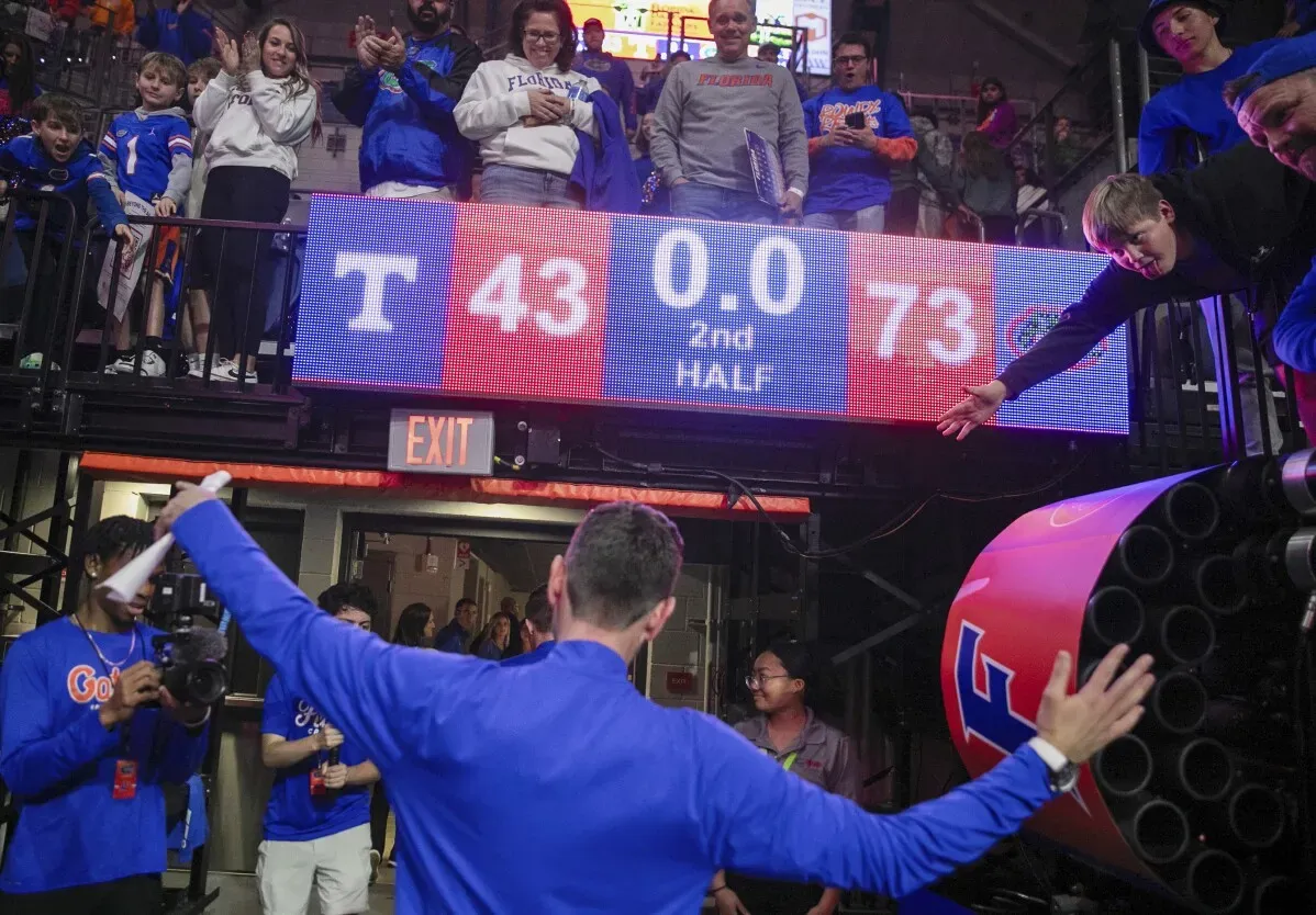 فريق فلوريدا يحتفل بفوزه على تينيسي بعد انتهاء المباراة 73-43، مع عرض النتيجة على الشاشة، والجمهور يشجع.