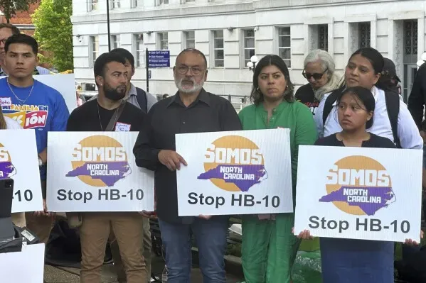 محتجون يحملون لافتات تعبر عن معارضتهم لقانون HB-10 في نورث كارولينا، مع التركيز على قضايا الهجرة وتأثيرها على المجتمعات.