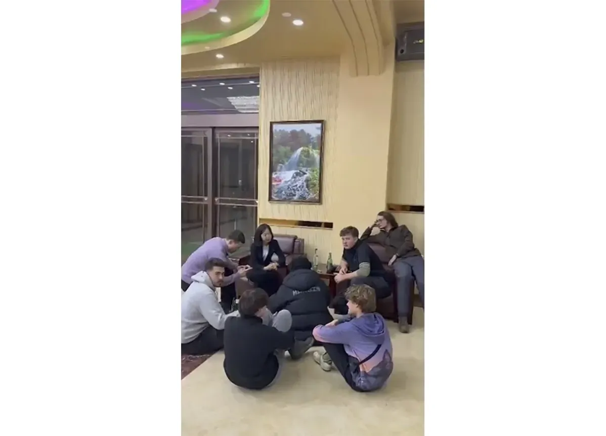 مجموعة من السياح الأجانب يجلسون في بهو فندق بكوريا الشمالية، حيث يشاركون في نشاط اجتماعي، مع وجود صورة طبيعية على الجدار.