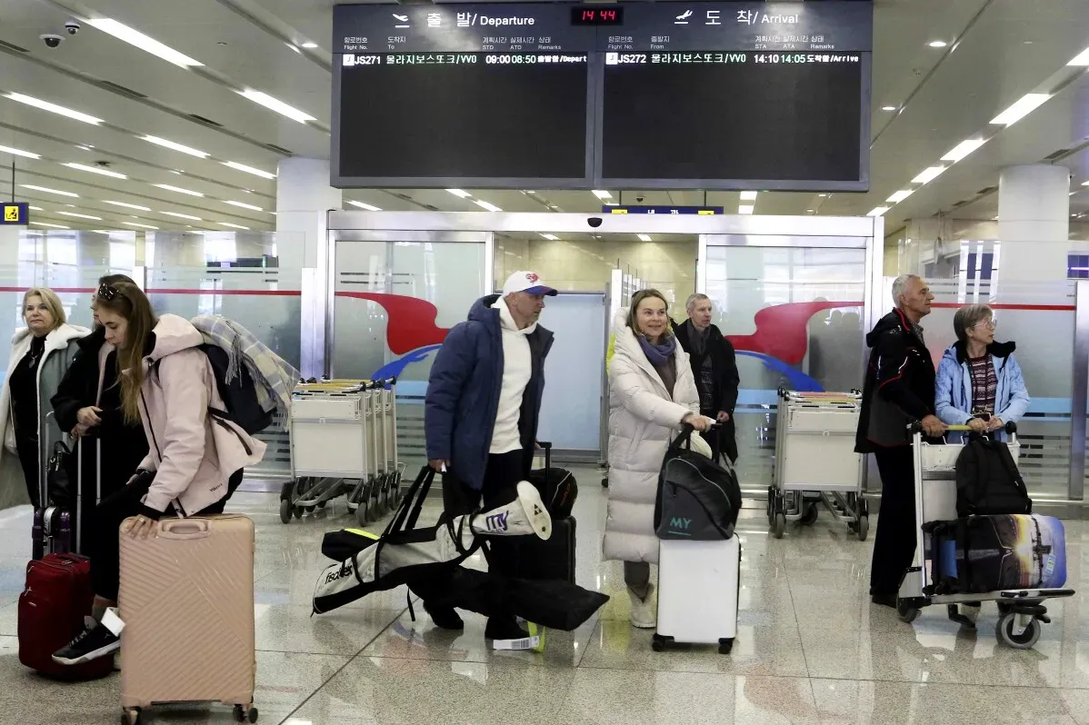 سياح دوليون يصلون إلى مطار في كوريا الشمالية، مع حقائبهم، في أول زيارة لهم منذ خمس سنوات، مما يشير إلى استئناف السياحة الدولية.