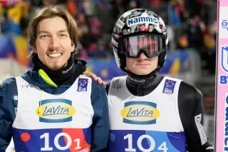 لاعبا تزلج نرويجيان يرتديان بدلات التزلج، يظهران في حدث رياضي، وسط أجواء تنافسية. تتعلق الصورة بفضيحة التلاعب بالبدلات.