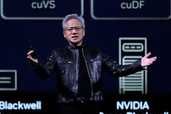 Jensen Huang يتحدث في مؤتمر، مرتديًا سترة جلدية، مع خلفية تعرض تقنيات الذكاء الاصطناعي لشركة Nvidia، مما يعكس تحول الصناعة الأمريكية.