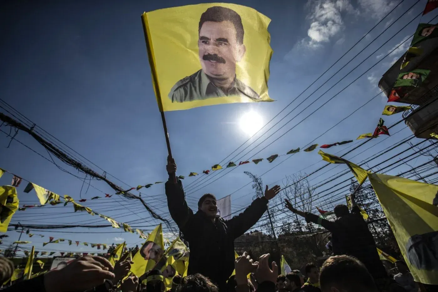 محتجون يحملون أعلاماً صفراء تحمل صورة عبد الله أوجلان، الزعيم المسجون لحزب العمال الكردستاني، خلال تجمع حاشد.