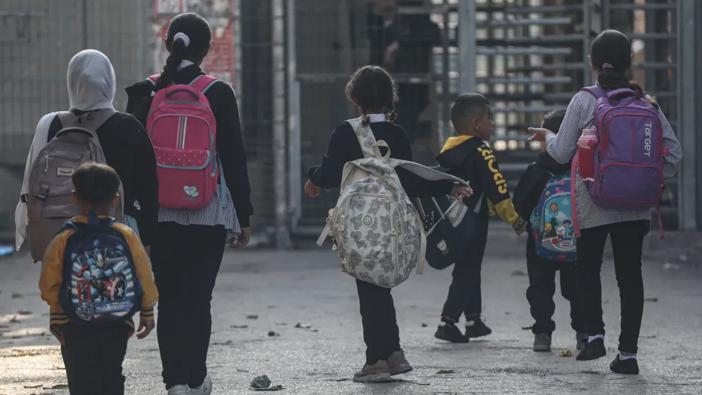 مجموعة من الأطفال يسيرون نحو المدرسة في رام الله، يحملون حقائبهم المدرسية، مع تراجع جودة التعليم في الضفة الغربية.
