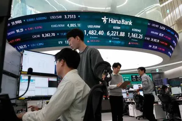 مستثمرون في غرفة تداول بأسواق الأسهم الآسيوية، مع عرض أسعار العملات والمؤشرات المالية على الشاشة. تعكس الصورة النشاط الاقتصادي وسط تقلبات أسعار النفط.