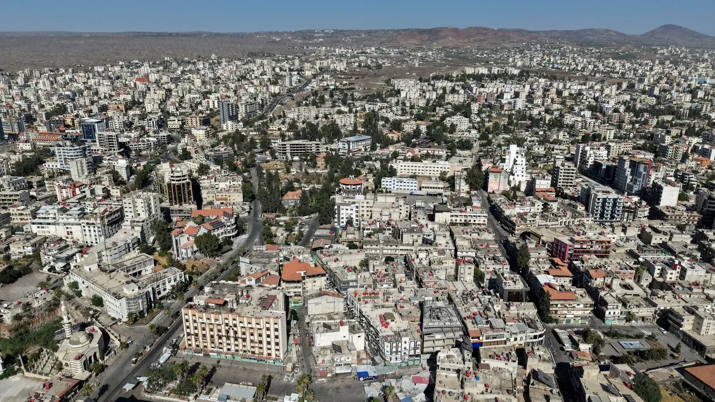 صورة جوية لمدينة السويداء في سوريا، تظهر التوترات الأمنية مع وجود المباني السكنية والمرافق العامة في المنطقة.