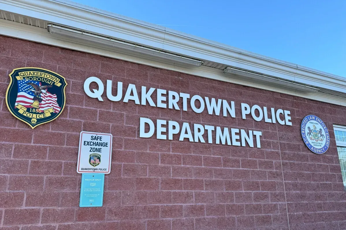 واجهة قسم شرطة كواكيرتاون، مع شعار القسم ولافتة تشير إلى منطقة تبادل آمن، تعكس السياق الاجتماعي والسياسي للاحتجاجات المحلية.