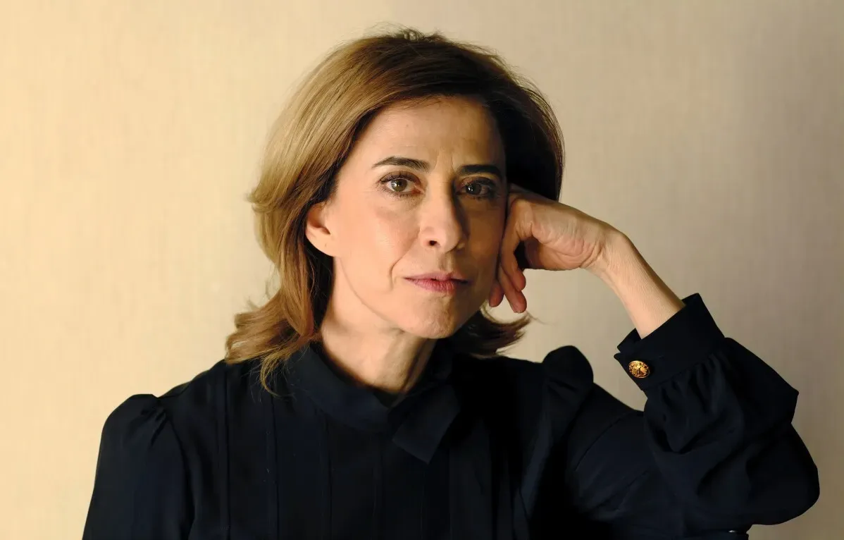 فرناندا توريس، مرشحة لجائزة أوسكار، تظهر بتعبير جاد، مرتدية ملابس سوداء، مع خلفية بسيطة، تعكس تركيز البرازيل على الثقافة والاحتفال.