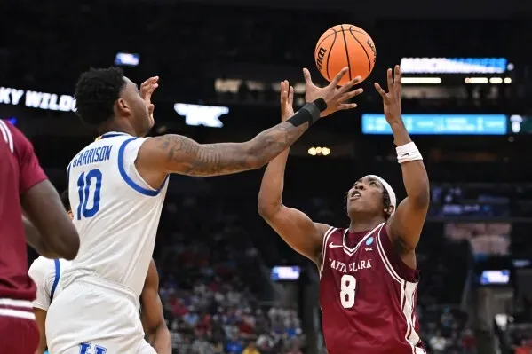 لاعب سانتا كلارا يسدد كرة سلة بينما يحاول لاعب كنتاكي الدفاع عنه، في مباراة مثيرة ضمن بطولة NCAA.