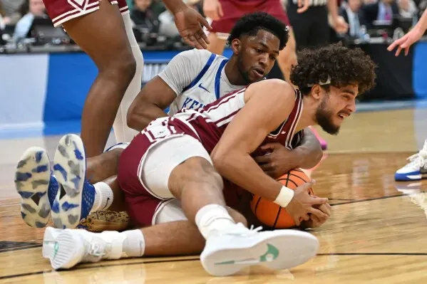 تسديدة مثيرة للاعب سانتا كلارا وهو يتصارع على الكرة مع لاعب كنتاكي خلال مباراة مثيرة في بطولة NCAA، حيث يسعى كل فريق لتحقيق الفوز.