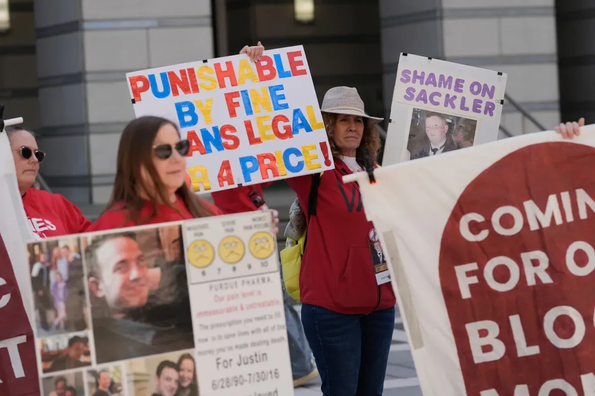 محتجون يحملون لافتات تعبر عن استيائهم من تسوية Purdue Pharma، مطالبين بالعدالة لضحايا أزمة المواد الأفيونية.