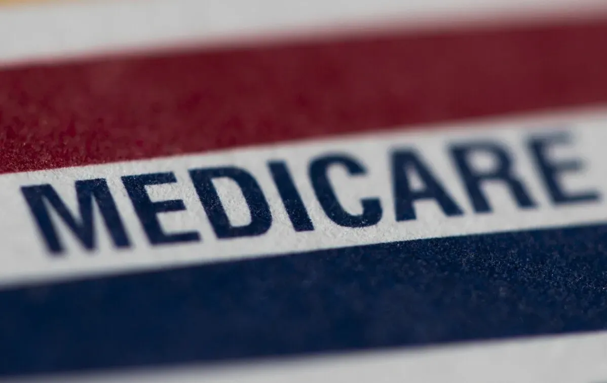 بطاقة ميديكير تُظهر كلمة \"MEDICARE\" بوضوح، مع تصميم بالألوان الأحمر والأزرق، تعكس التغييرات في أسعار الأدوية.