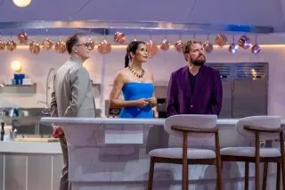 بادما لاكشمي تتوسط طاولة التحكيم في برنامج "كأس أمريكا للطهي"، مع حكام آخرين، في مطبخ حديث مزود بأدوات طهي متطورة.