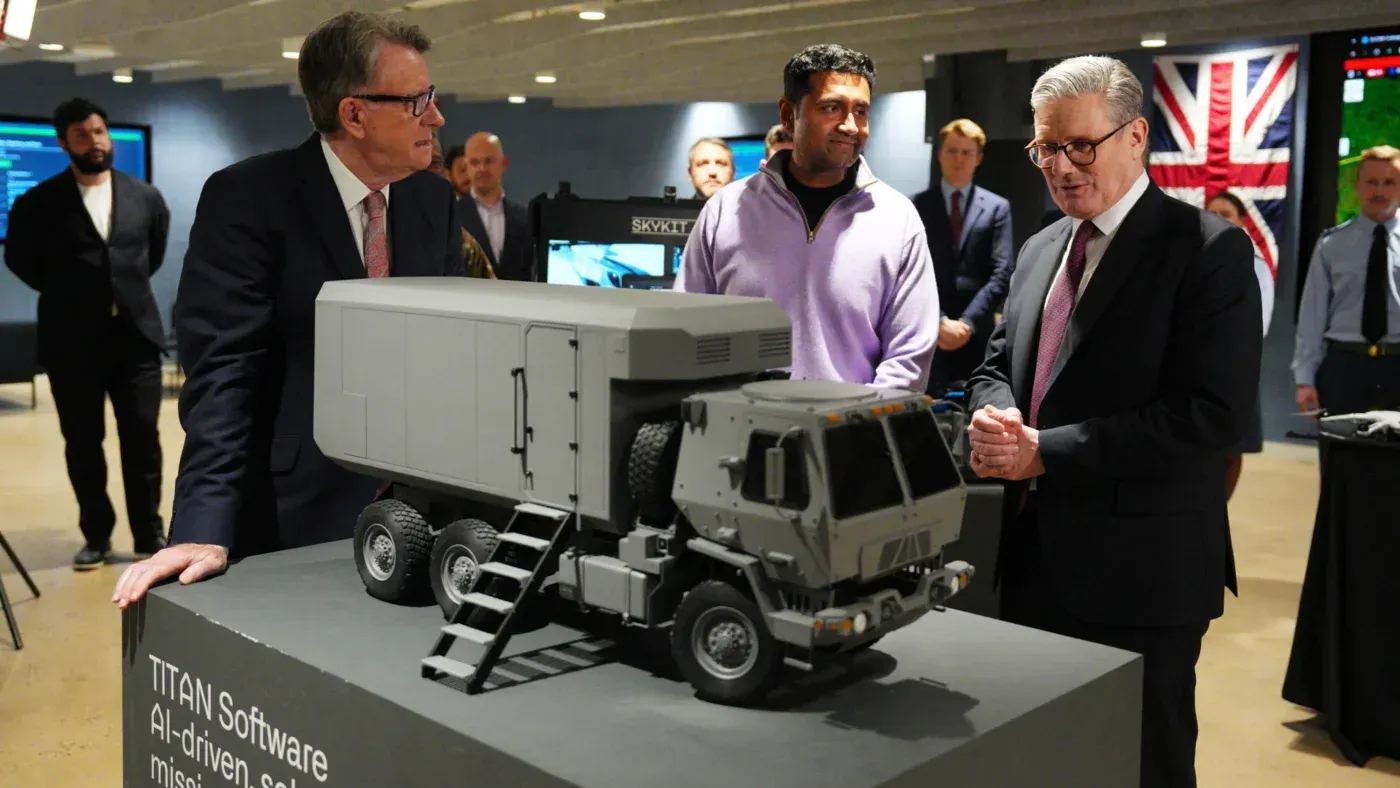 عرض نموذج لمركبة عسكرية مزودة بتقنية الذكاء الاصطناعي، مع مسؤولين يتناقشون حول استخدامات البيانات في الدفاع.