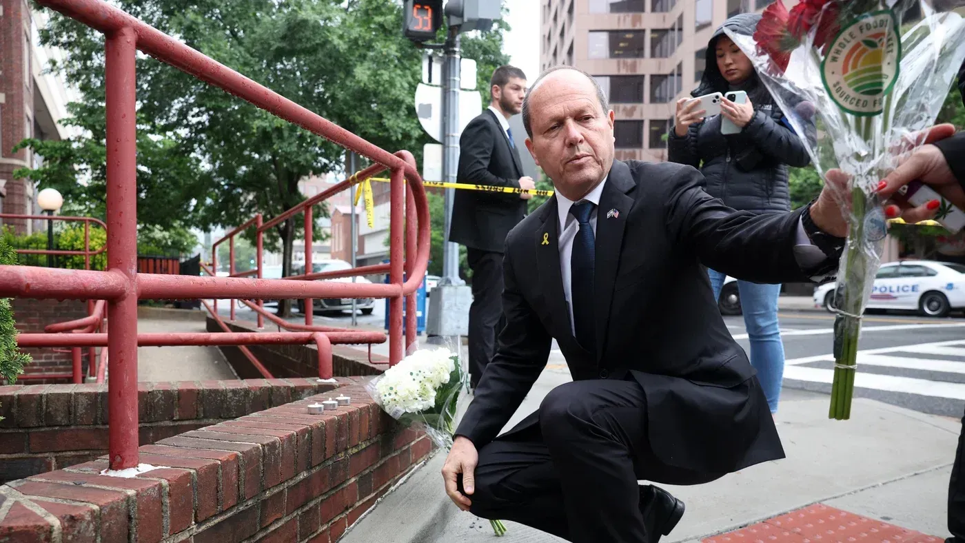 وزير الاقتصاد الإسرائيلي نير بركات يضع زهورًا قرب موقع حادث، محاطًا بالصحفيين وأفراد الأمن، في سياق الشكوى الجنائية ضده.