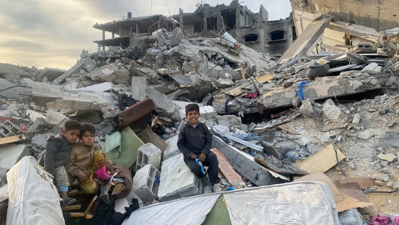 أطفال يجلسون على أنقاض منزل مدمّر في شمال غزة، يعبرون عن معاناتهم بعد الحرب الإسرائيلية وما خلفته من دمار.